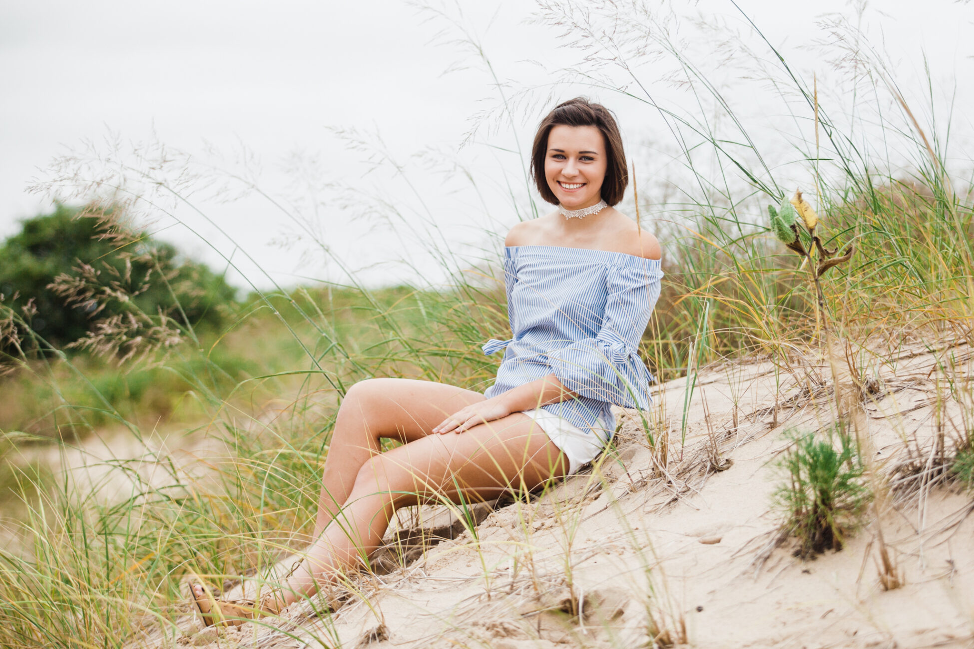 senior girl sitting on sand dune with dune grass